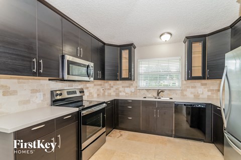 A kitchen with black cabinets and a FirstKey Homes logo.