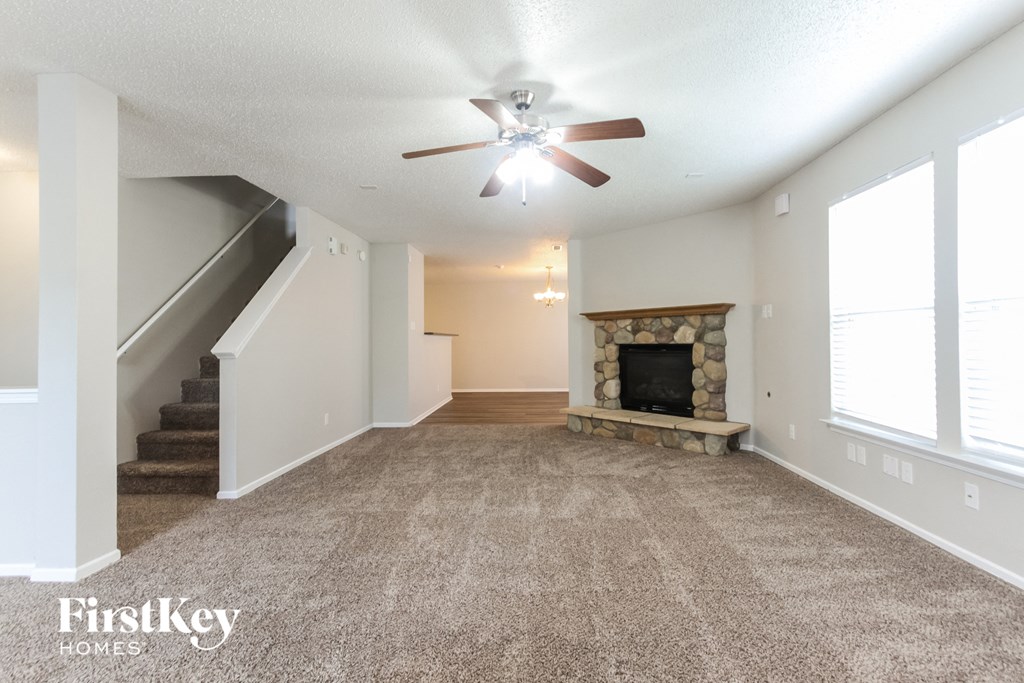 A spacious living room with a fireplace and a carpeted floor.