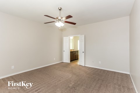 a living room with a ceiling fan and a carpet