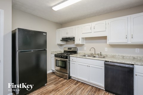 a kitchen with white cabinets and a black refrigerator