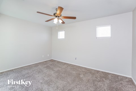 the spacious living room with ceiling fan and carpet