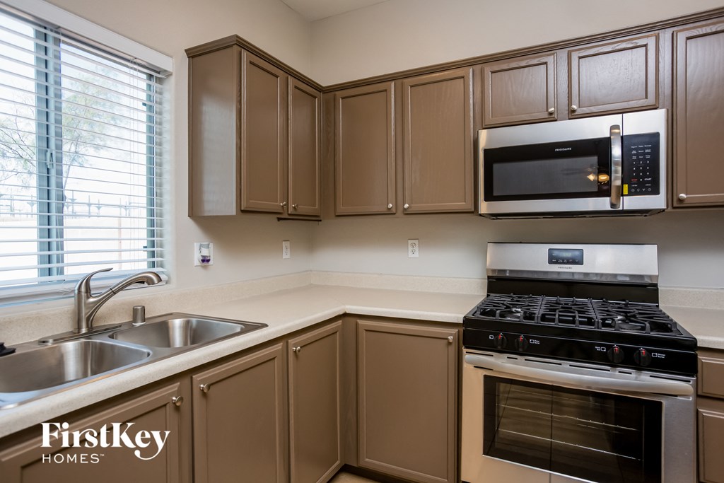 a kitchen with brown cabinets and black appliances and a sink
