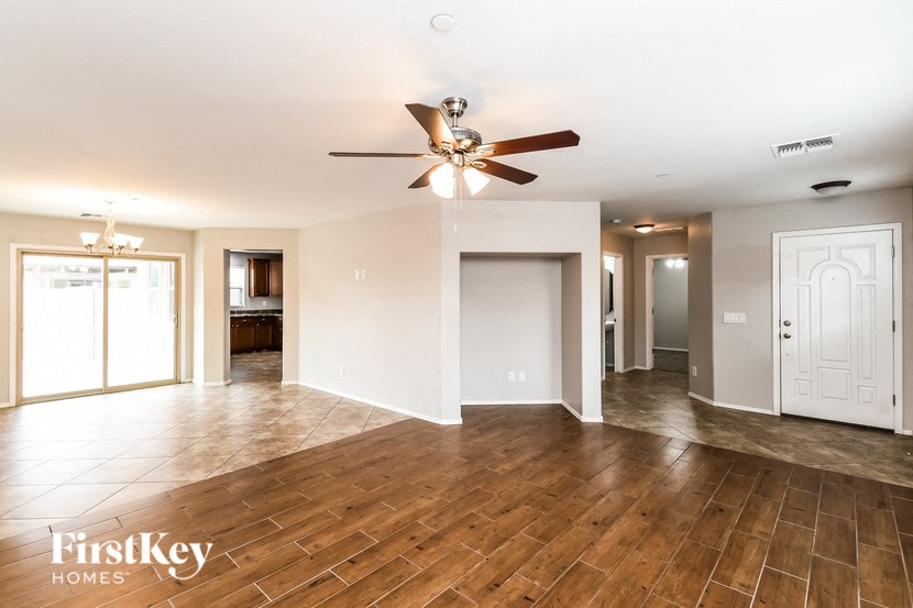 an empty living room with wood floors and a ceiling fan
