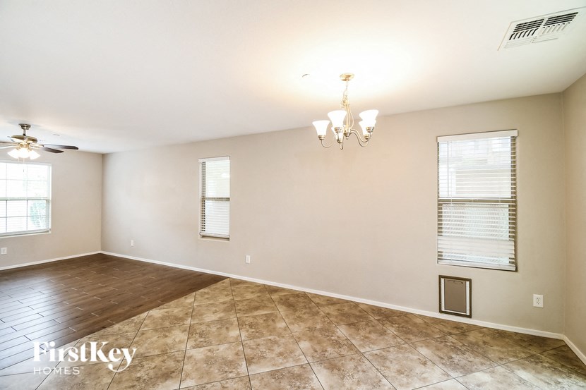 an empty living room with tile floors and a ceiling fan