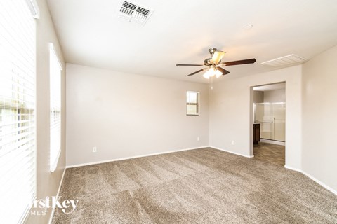a spacious living room with carpet and a ceiling fan