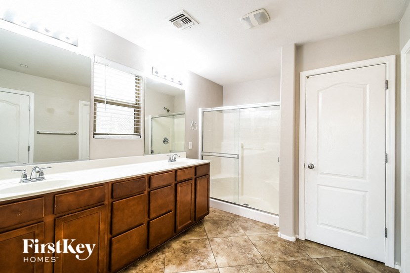 the master bathroom has a large vanity with a large mirror and a walk in shower
