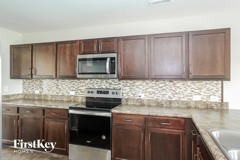 A kitchen with brown cabinets and a black stove top oven.