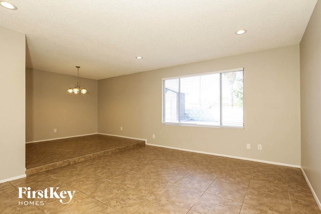A spacious empty room with a large window and a chandelier.