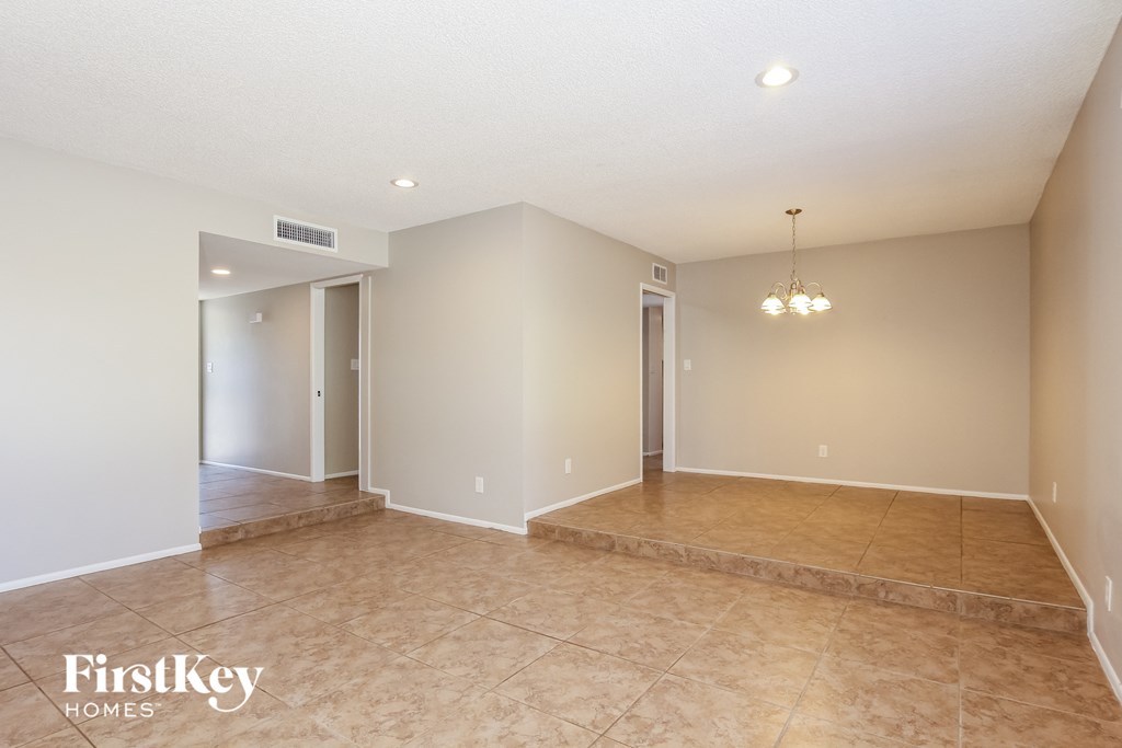 A spacious room with a tiled floor and a chandelier hanging from the ceiling.