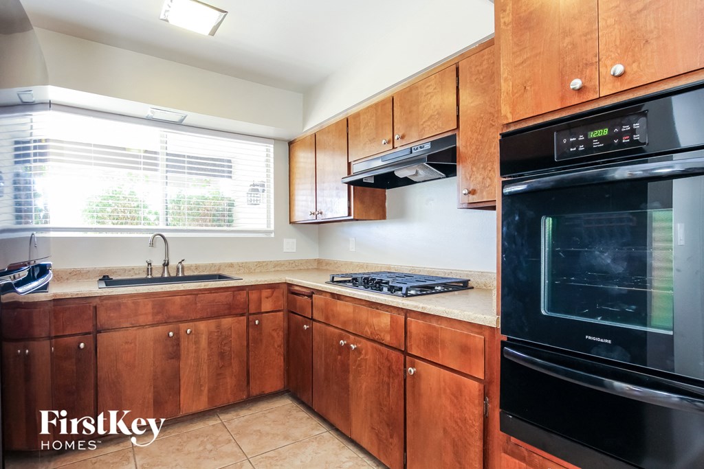 A kitchen with wooden cabinets and a black stove top oven.