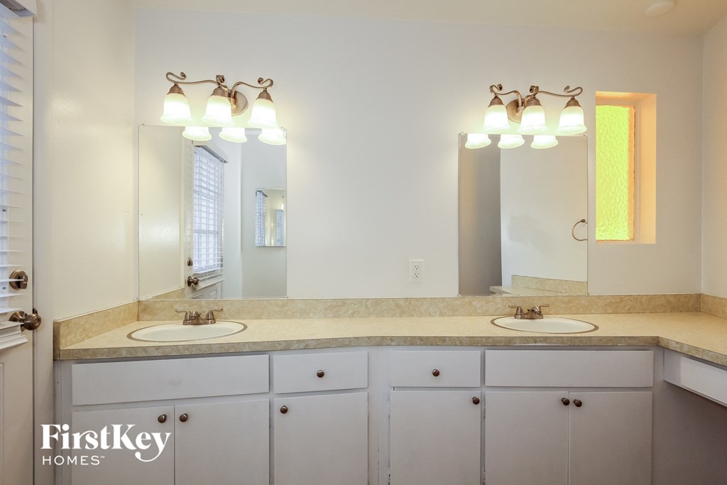 A bathroom with a double sink vanity and a large mirror above it.