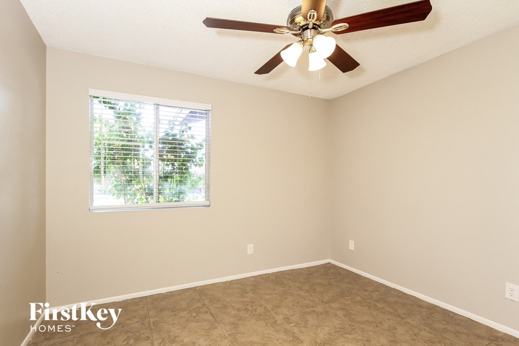 A room with a ceiling fan and a window letting in natural light.