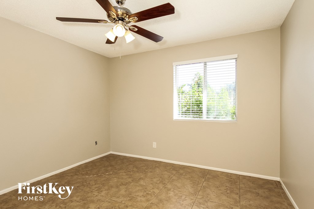 A room with a ceiling fan and a window with blinds.