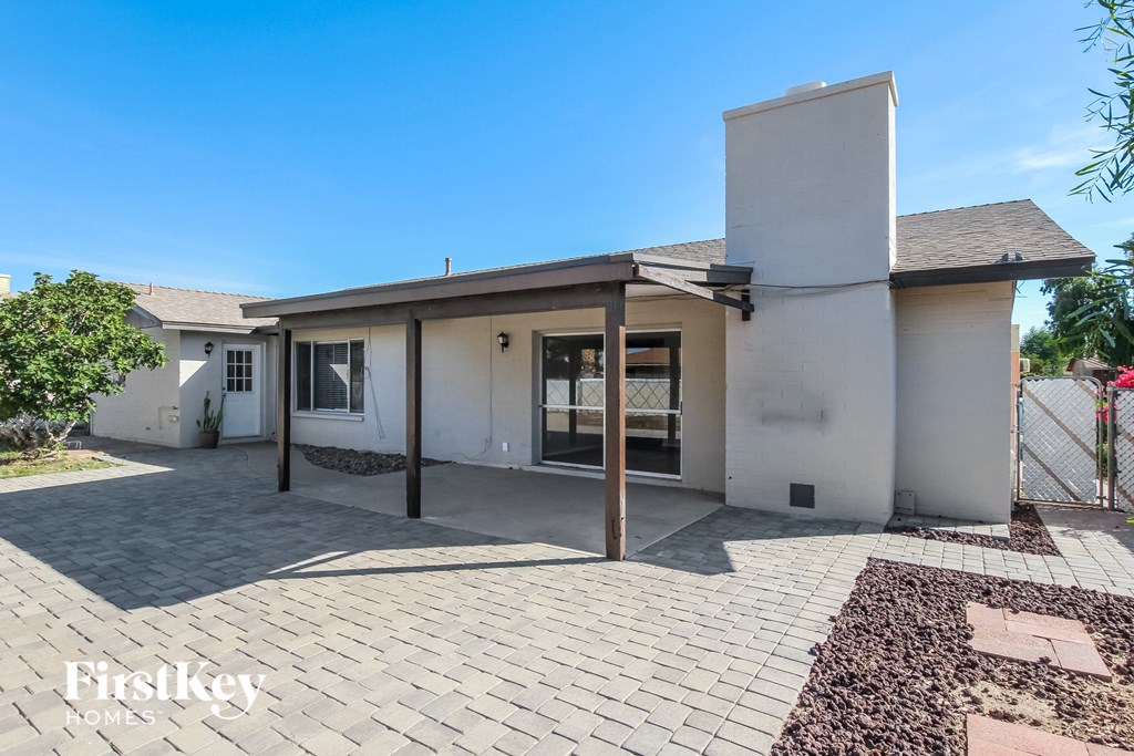 A house with a white exterior and a brick patio is for sale.