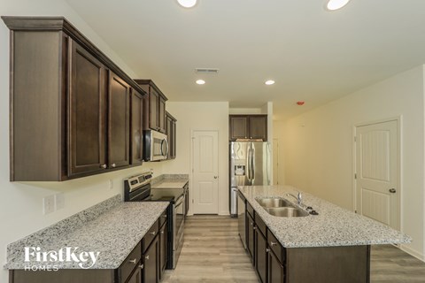 A kitchen with dark brown cabinets and a granite countertop.