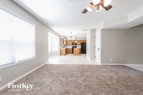 A spacious room with a carpeted floor and a ceiling fan.