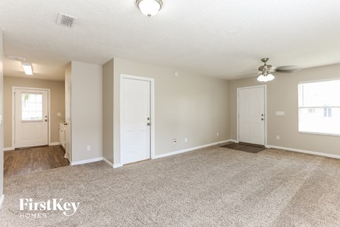 a spacious living room with carpet and a ceiling fan