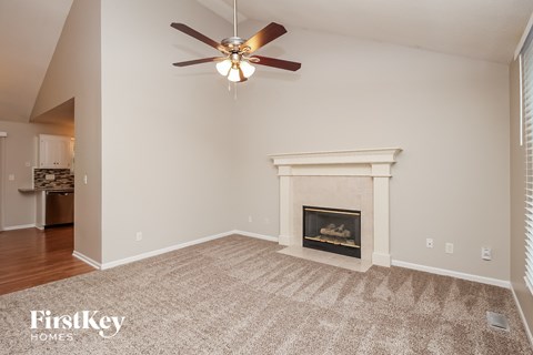 A living room with a fireplace and a ceiling fan.