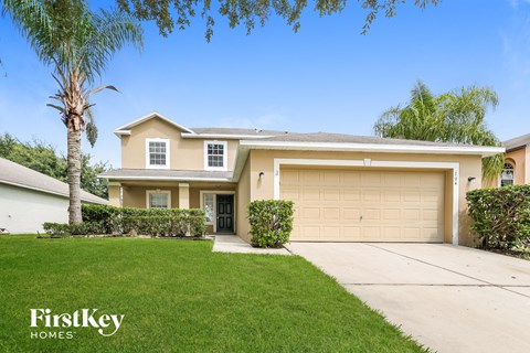 a beige house with a garage door and a lawn