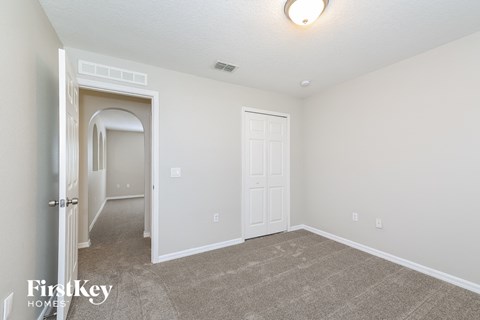 a bedroom with a carpeted floor and a door to a hallway