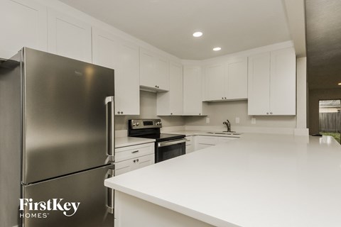 a white kitchen with stainless steel appliances and white counter tops