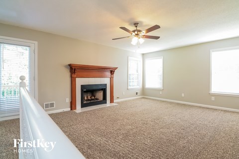A spacious living room with a fireplace and a carpeted floor.
