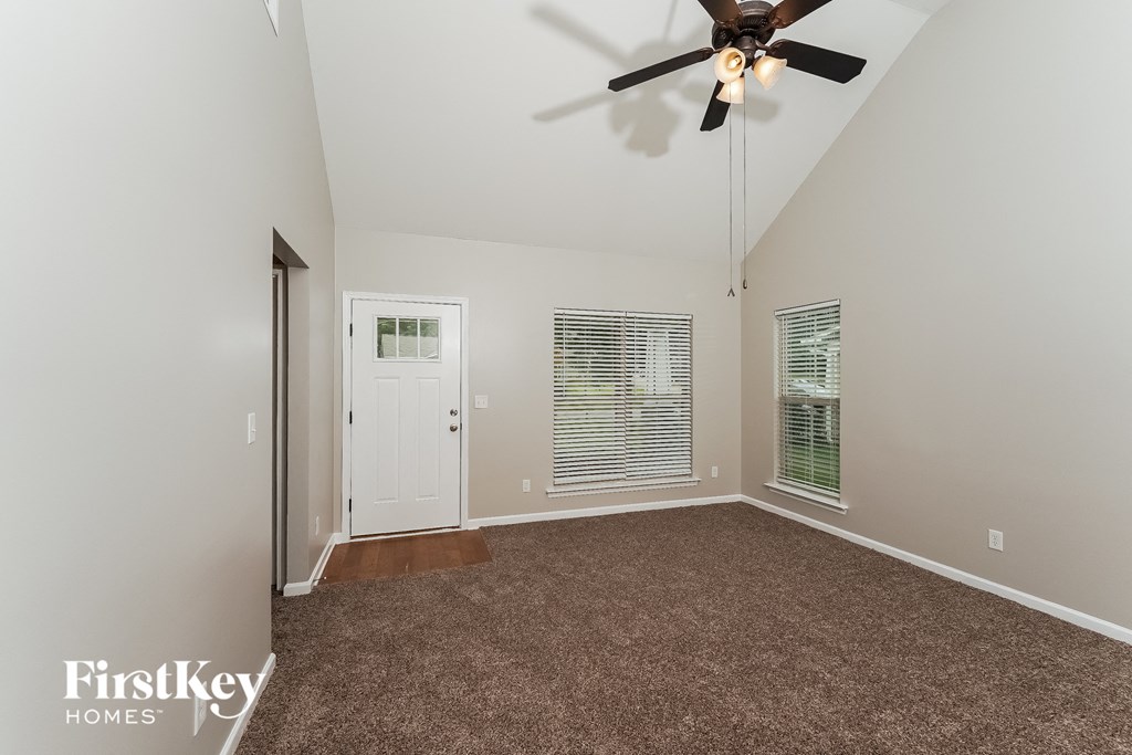 the living room is spacious and has a ceiling fan