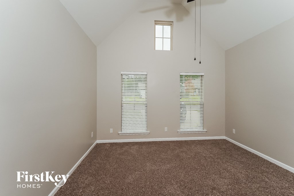 an empty living room with carpet and two windows