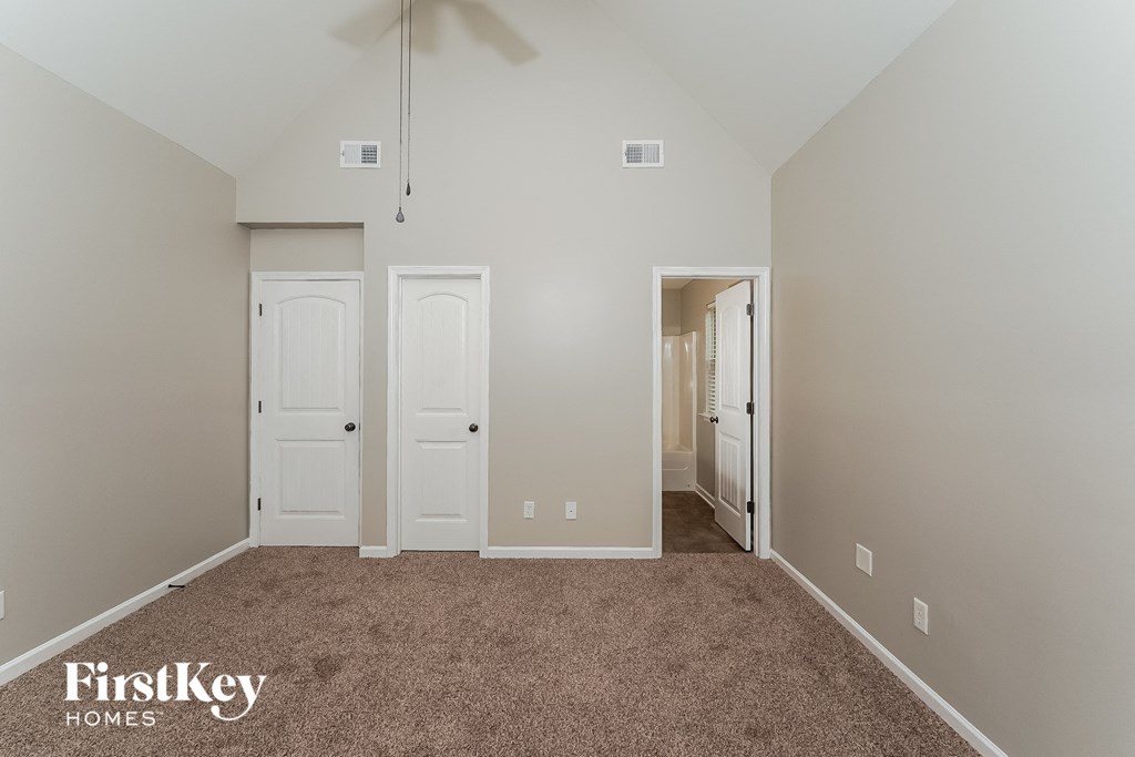 a bedroom with carpet and two closets and a door to a hallway