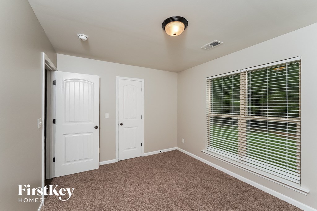 a bedroom with a large window and a door and a carpeted floor