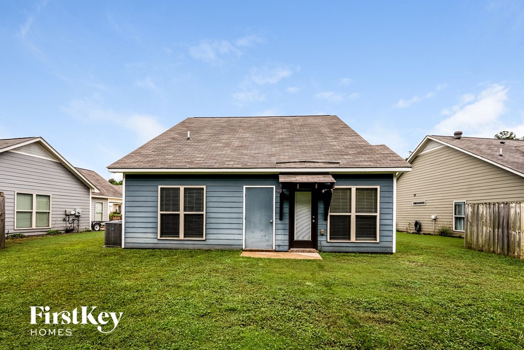 the front of a blue house with a yard and a fence