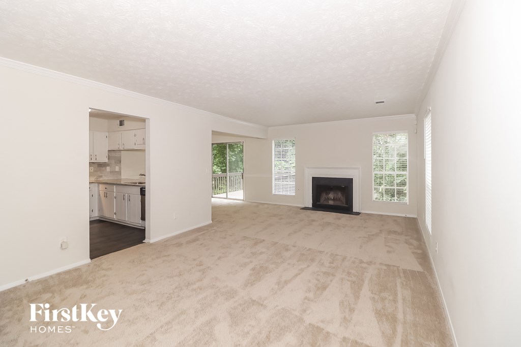 A large empty room with a fireplace and a window.