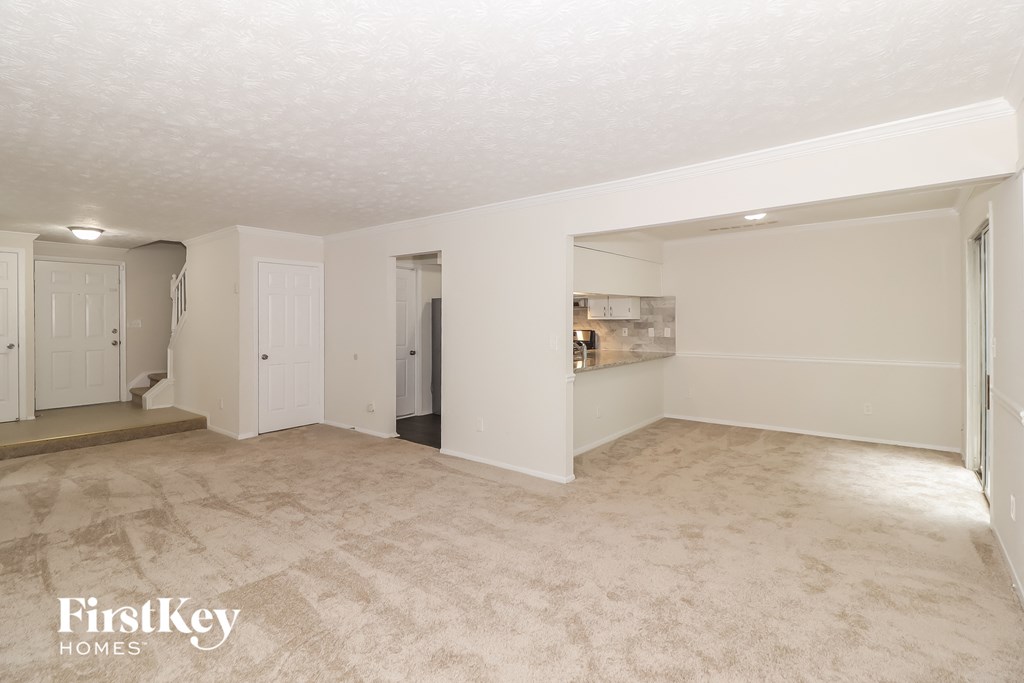 A spacious empty room with a carpeted floor and white walls.
