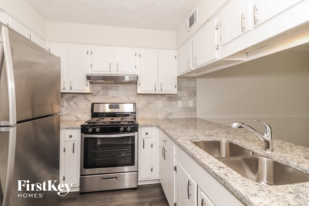 A kitchen with a stainless steel refrigerator, oven, and sink.