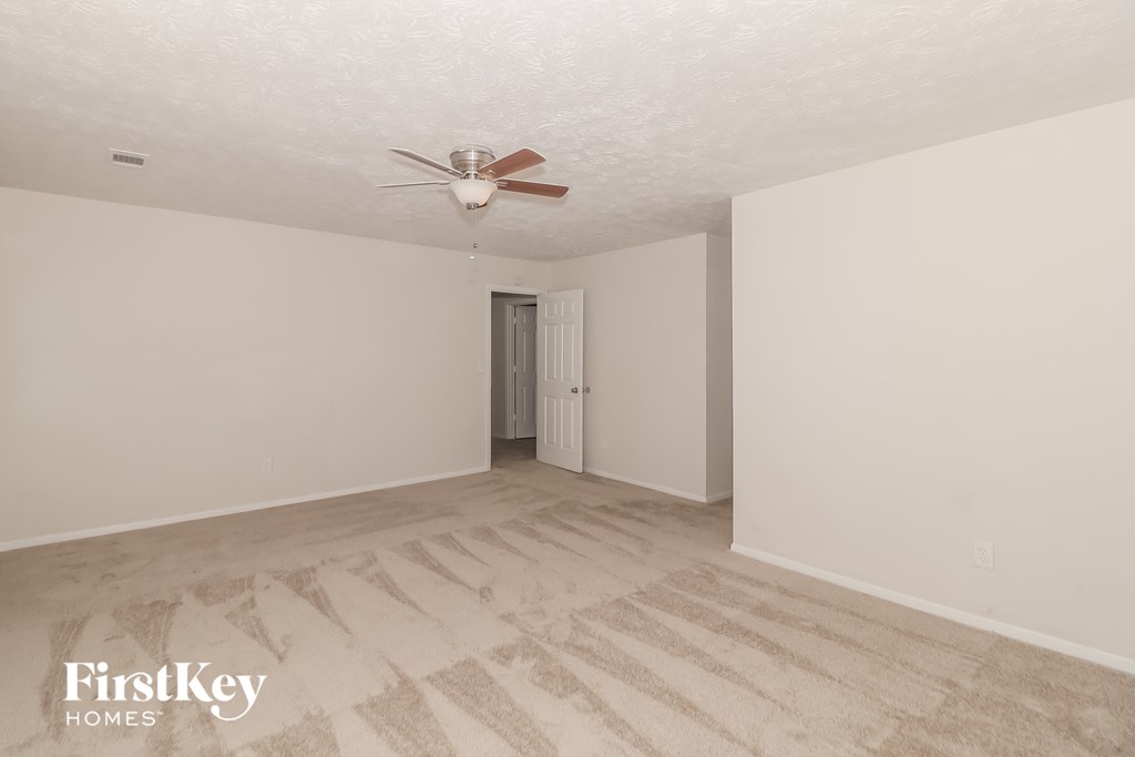 A room with a fan and a door leading to a bathroom.