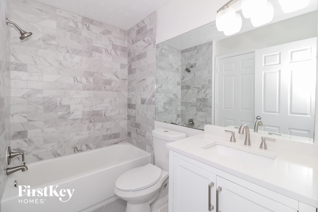 A white bathroom with a marble tile shower.