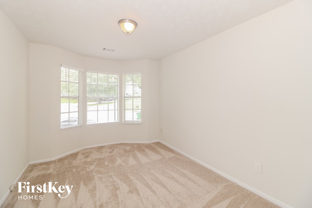 A room with a carpeted floor and a window with blinds.