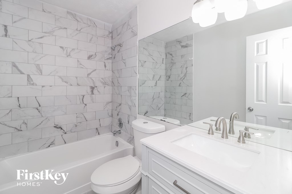 A white bathroom with a marble tile wall.