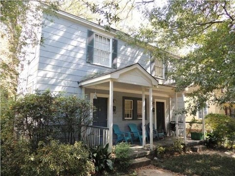 a blue house with a porch with blue chairs