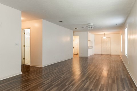 the living room and dining room of an empty house with wood floors and white walls