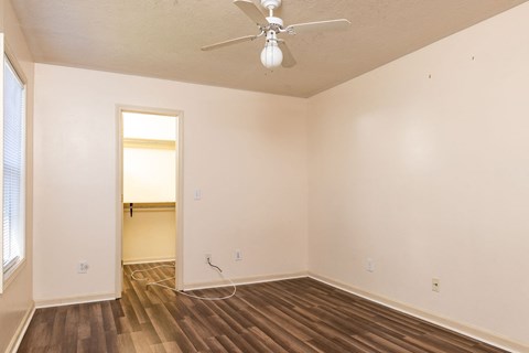 the spacious living room of an empty home with a ceiling fan