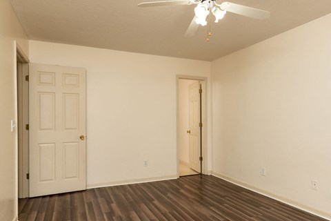 the spacious living room of an empty home with a ceiling fan