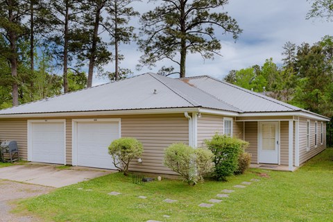 a small tan house with white garage doors