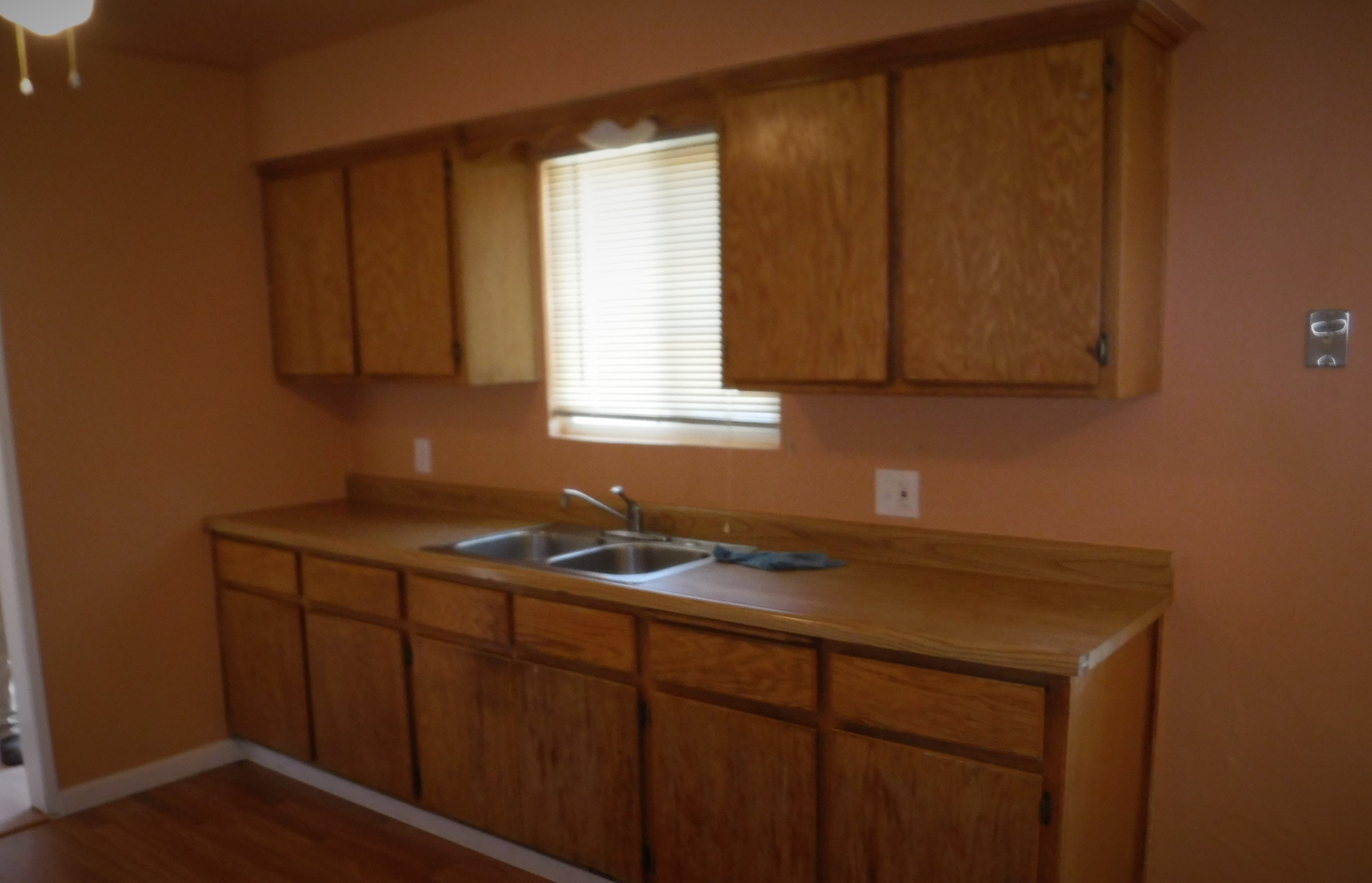 an empty kitchen with a sink and wooden cabinets