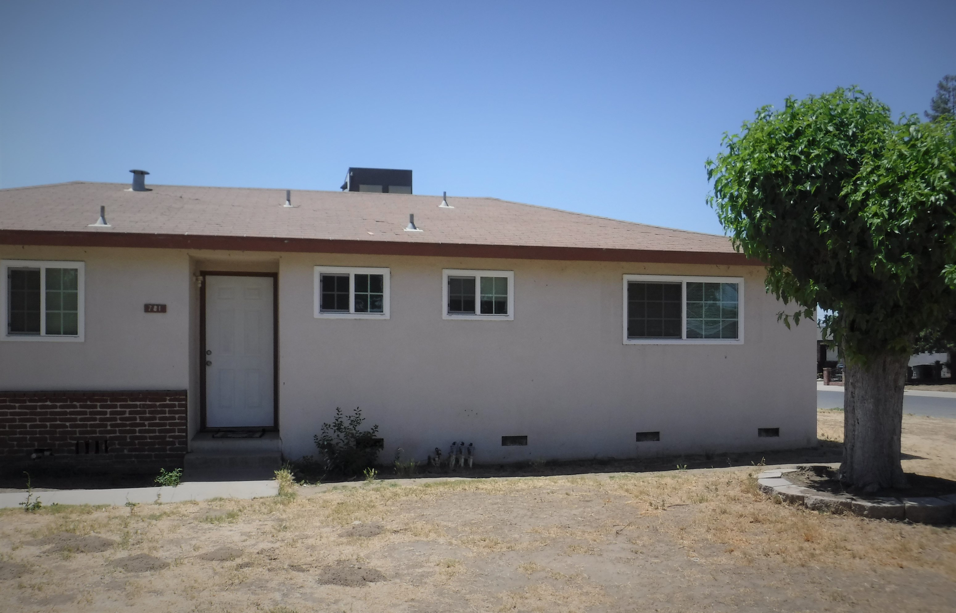 the front of a white house with a tree