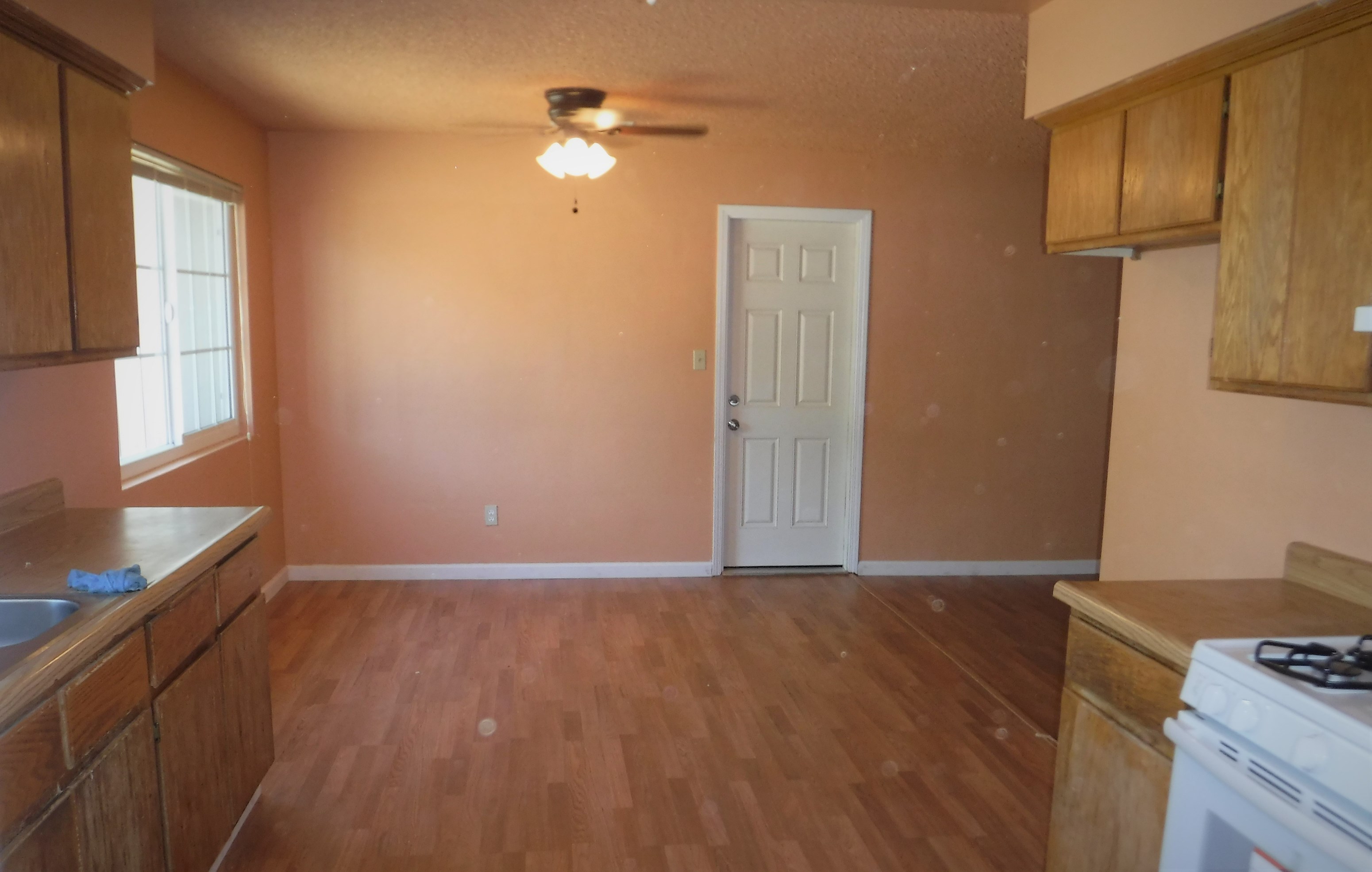 an empty kitchen with wooden floors and a white door