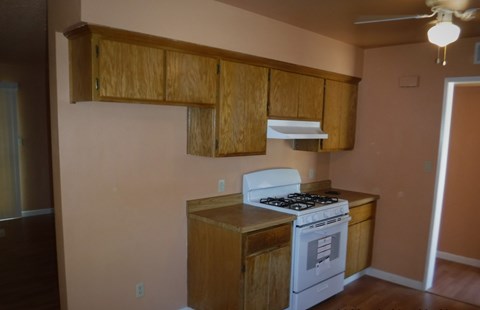 a kitchen with a stove and cabinets and a ceiling fan