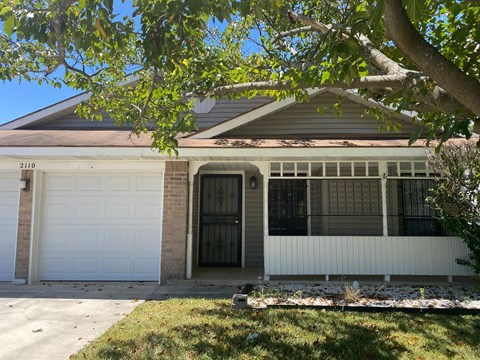 A house with a white garage door and a brick pillar.