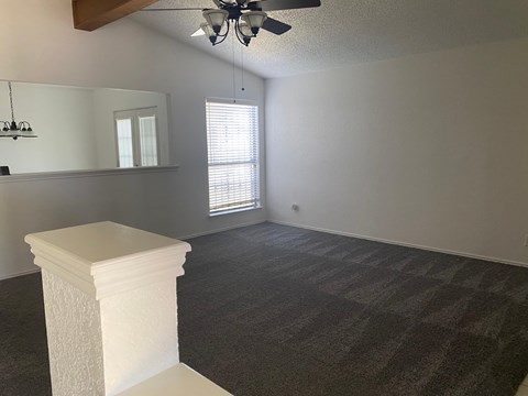 A room with a carpeted floor and a white pedestal in the foreground.