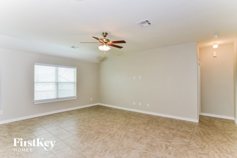 A spacious room with a ceiling fan and a window with blinds.